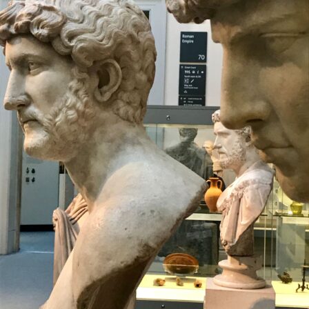 Perfil de dos bustos clásicos masculinos expuestos en una sala de mueso.