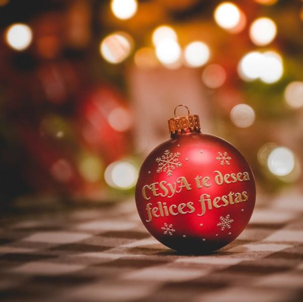Imagen de una bola de adorno de un árbol de Navidad roja con letras doradas que dicen: "CESyA te desea felices fiestas"