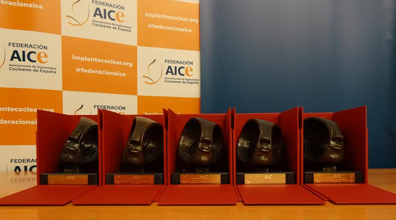Cinco premios AICE esperan a ser entregados dentro de sus cajas, abiertas, de color rojo. 