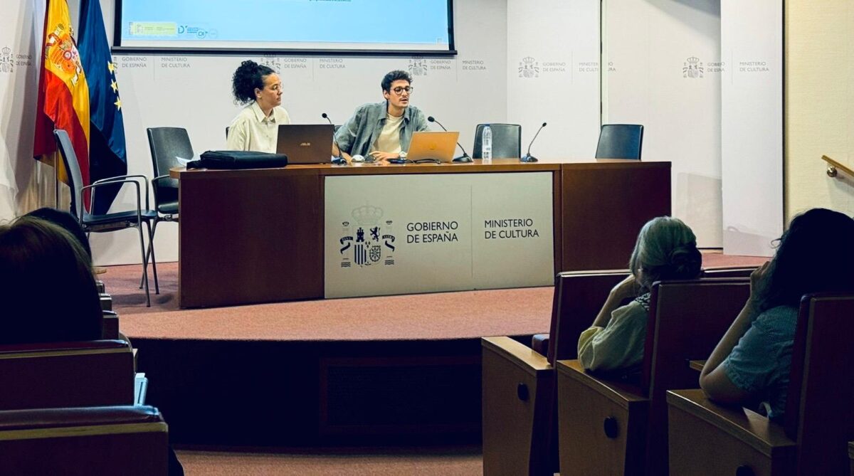 Dos miembros de CESyA, sentados tras una gran mesa de madera con el logo del Ministerio de Cultura, exponen el contenido de la formación. Frente a ellos, en un patio de butacas, están sentados los asistentes al taller.